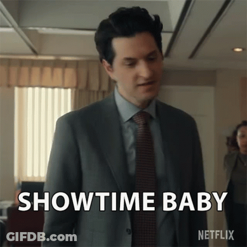 A Man In A Suit And Tie Is Standing In An Office And Says Showtime Baby . GIF