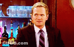 A Man In A Suit And Tie Is Standing In Front Of A Bar Full Of Bottles GIF
