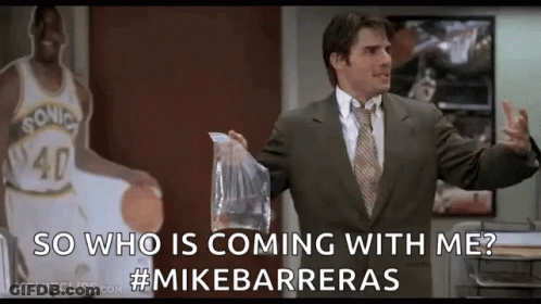 A Man In A Suit And Tie Is Standing In Front Of A Basketball Player Holding A Bag Of Food . GIF
