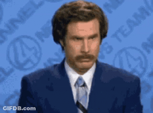 A Man In A Suit And Tie Is Standing In Front Of A Blue Background GIF