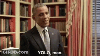 A Man In A Suit And Tie Is Standing In Front Of A Bookshelf And Says " Yolo , Man " . GIF