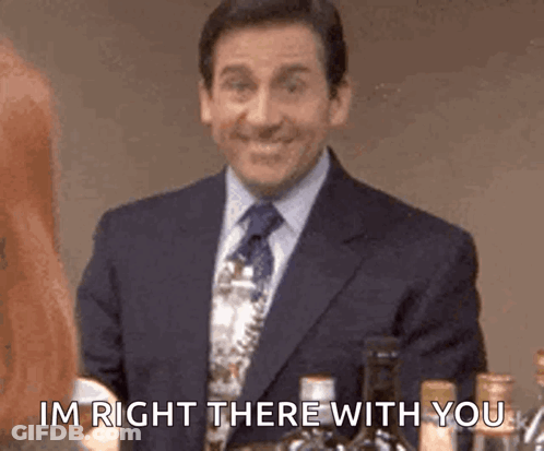 A Man In A Suit And Tie Is Standing In Front Of A Bottle Of Wine And Says `` Im Right There With You '' . GIF