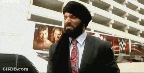 A Man In A Suit And Tie Is Standing In Front Of A Building With A W Logo On It . GIF