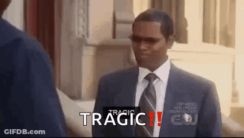 A Man In A Suit And Tie Is Standing In Front Of A Building With The Word Tragic Written On The Bottom Of The Screen . GIF