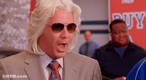 A Man In A Suit And Tie Is Standing In Front Of A Buy Sign GIF