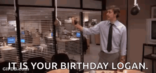 A Man In A Suit And Tie Is Standing In Front Of A Cake In An Office . GIF