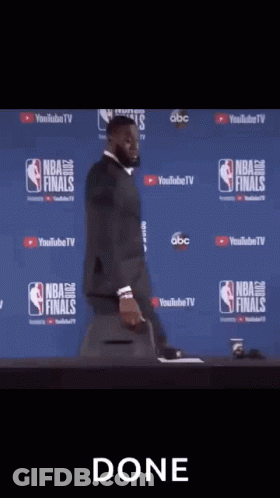 A Man In A Suit And Tie Is Standing In Front Of A Camera With The Word Done On The Bottom GIF