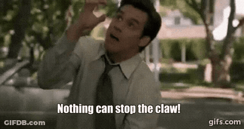 A Man In A Suit And Tie Is Standing In Front Of A Car And Says Nothing Can Stop The Claw . GIF