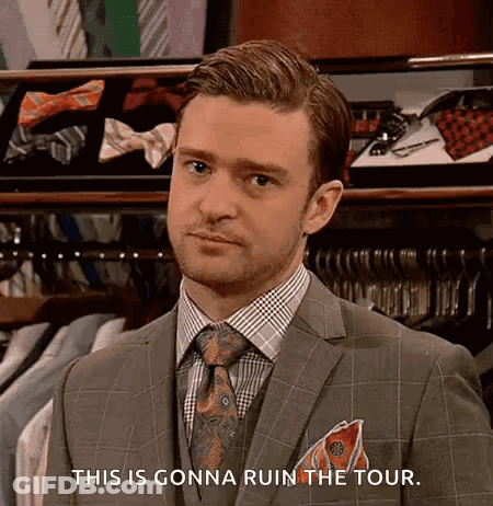 A Man In A Suit And Tie Is Standing In Front Of A Closet Filled With Shirts And Ties . GIF