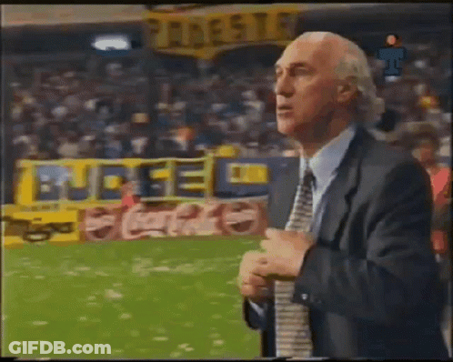 A Man In A Suit And Tie Is Standing In Front Of A Coca Cola Banner GIF
