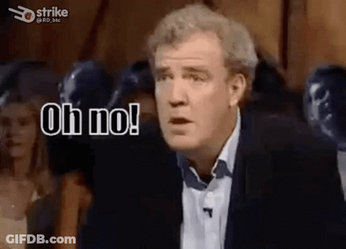 A Man In A Suit And Tie Is Standing In Front Of A Crowd And Saying Oh No . GIF