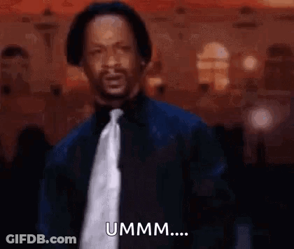 A Man In A Suit And Tie Is Standing In Front Of A Crowd And Saying Ummm . GIF