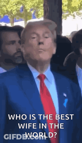 A Man In A Suit And Tie Is Standing In Front Of A Crowd And Says `` Who Is The Best Wife In The World ? '' GIF