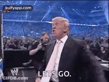 A Man In A Suit And Tie Is Standing In Front Of A Crowd And Screaming . GIF
