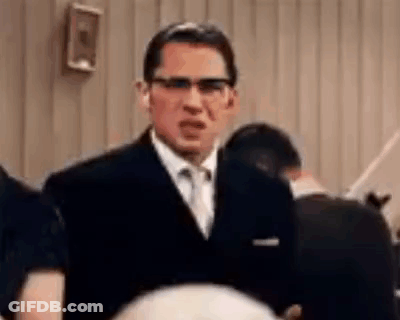 A Man In A Suit And Tie Is Standing In Front Of A Crowd . GIF