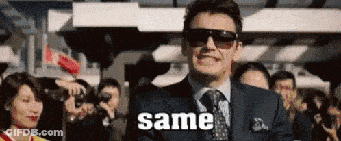 A Man In A Suit And Tie Is Standing In Front Of A Crowd Of People And Saying Same . GIF