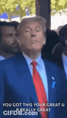 A Man In A Suit And Tie Is Standing In Front Of A Crowd . GIF