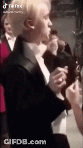 A Man In A Suit And Tie Is Standing In Front Of A Crowd . GIF