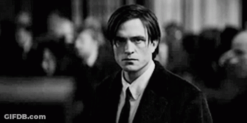 A Man In A Suit And Tie Is Standing In Front Of A Crowd . GIF
