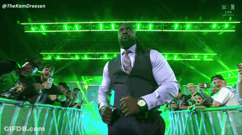 A Man In A Suit And Tie Is Standing In Front Of A Crowd With The Letters N On The Bottom Right GIF