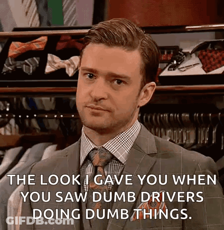 A Man In A Suit And Tie Is Standing In Front Of A Display Of Ties And Shirts . GIF