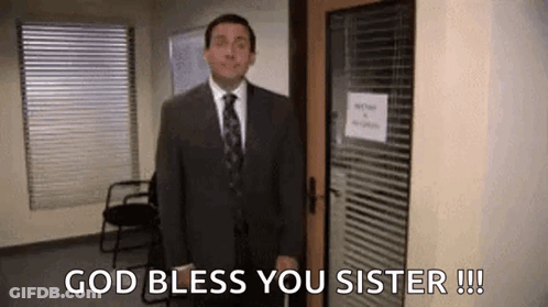A Man In A Suit And Tie Is Standing In Front Of A Door And Says `` God Bless You Sister '' . GIF