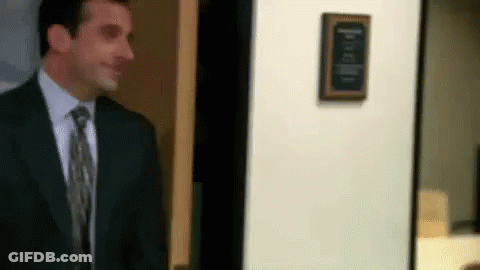 A Man In A Suit And Tie Is Standing In Front Of A Door In An Office . GIF