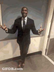 A Man In A Suit And Tie Is Standing In Front Of A Door With His Arms Outstretched GIF