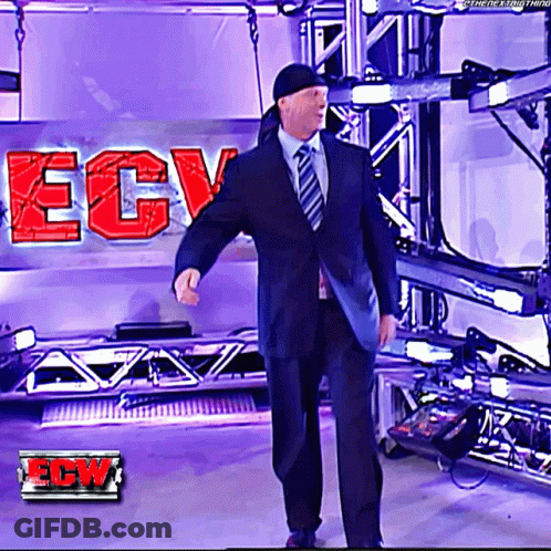 A Man In A Suit And Tie Is Standing In Front Of A Ecw Logo GIF
