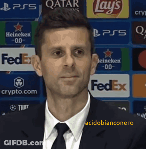 A Man In A Suit And Tie Is Standing In Front Of A Fedex Banner GIF