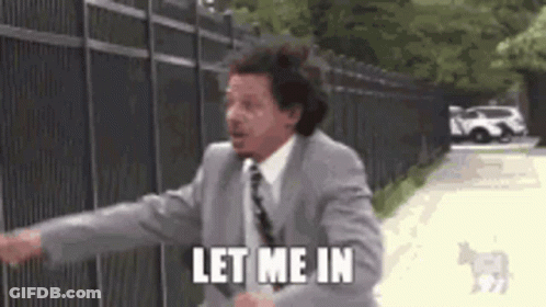 A Man In A Suit And Tie Is Standing In Front Of A Fence And Says `` Let Me In '' . GIF