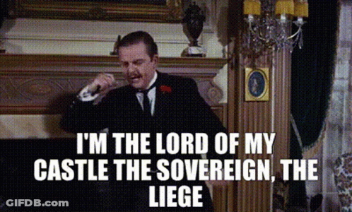 A Man In A Suit And Tie Is Standing In Front Of A Fireplace And Talking On A Phone . GIF