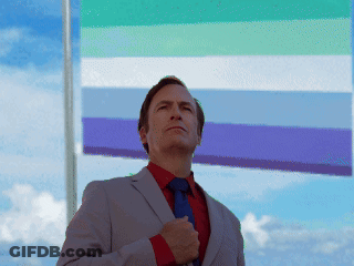 A Man In A Suit And Tie Is Standing In Front Of A Flag GIF