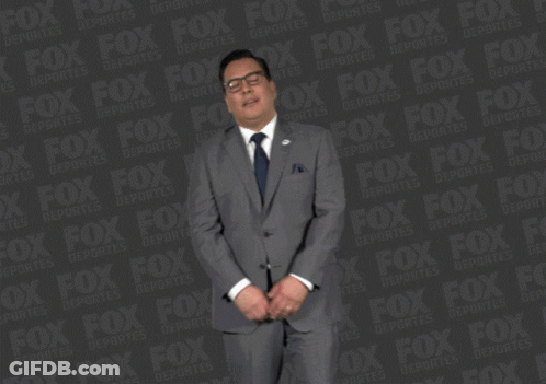 A Man In A Suit And Tie Is Standing In Front Of A Fox Logo GIF