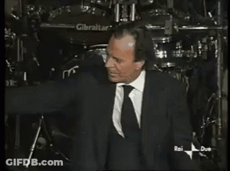 A Man In A Suit And Tie Is Standing In Front Of A Gibraltar Drum GIF