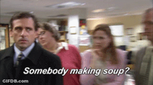 A Man In A Suit And Tie Is Standing In Front Of A Group Of People And Says Somebody Making Soup GIF