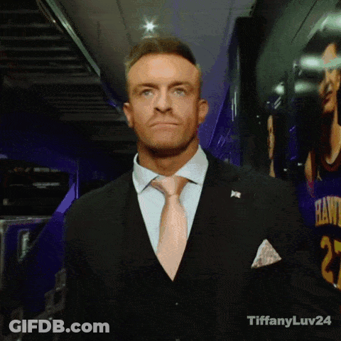 A Man In A Suit And Tie Is Standing In Front Of A Hawks Jersey GIF