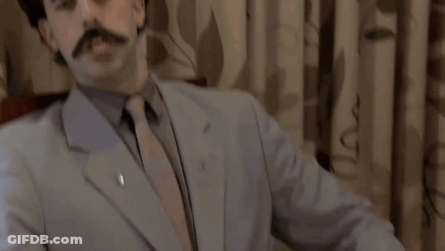A Man In A Suit And Tie Is Standing In Front Of A King Sign GIF