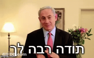 A Man In A Suit And Tie Is Standing In Front Of A Lamp And Flowers With The Words " Imgflip.com " Above Him GIF