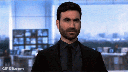 A Man In A Suit And Tie Is Standing In Front Of A Large Window GIF