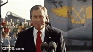A Man In A Suit And Tie Is Standing In Front Of A Microphone . GIF