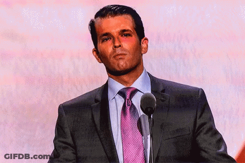 A Man In A Suit And Tie Is Standing In Front Of A Microphone GIF
