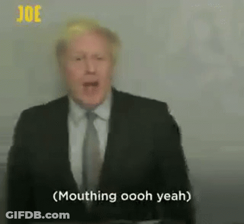 A Man In A Suit And Tie Is Standing In Front Of A Microphone . GIF