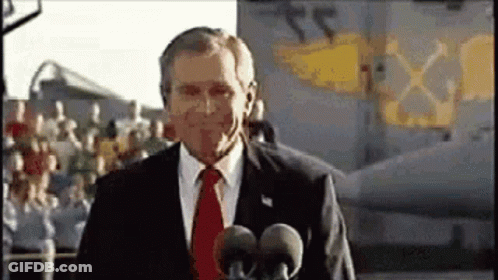 A Man In A Suit And Tie Is Standing In Front Of A Microphone . GIF