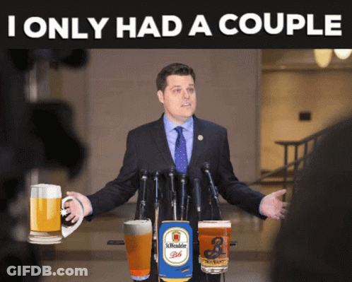 A Man In A Suit And Tie Is Standing In Front Of A Microphone With A Can Of St. Wendel Beer On The Podium GIF