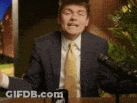 A Man In A Suit And Tie Is Standing In Front Of A Microphone With His Arms Outstretched GIF