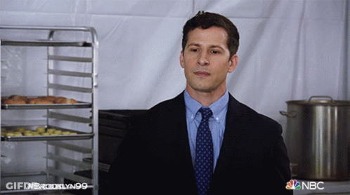 Man In Suit And Tie In Front Of NBC Ad GIF