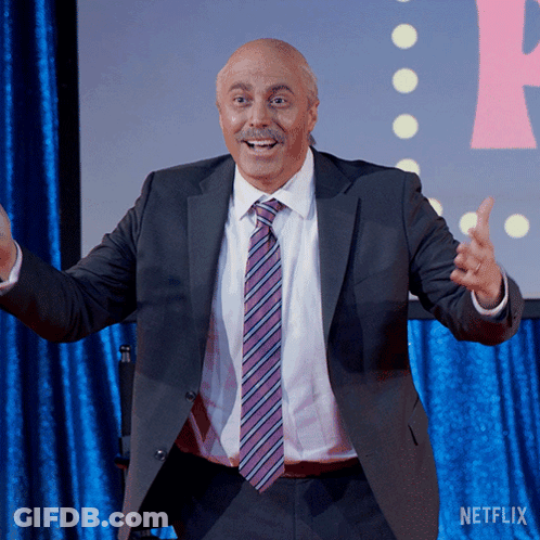 A Man In A Suit And Tie Is Standing In Front Of A Netflix Sign GIF