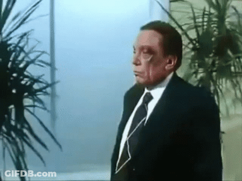Man In Suit And Tie Standing In Front Of Plant GIF