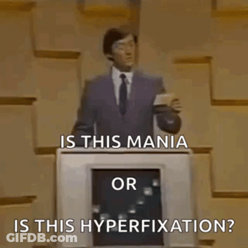 A Man In A Suit And Tie Is Standing In Front Of A Podium And Asking Is This Mania Or Is This Hyperfixation ? GIF